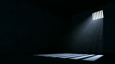 stock-footage-a-slow-pan-of-an-empty-dark-jail-cell-with-light-rays-penetrating-a-barred-window